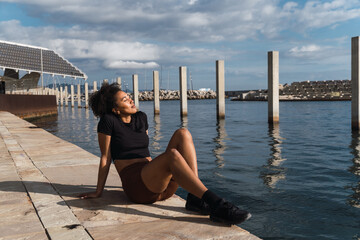 Young lady relaxing by the ocean after her exercise session