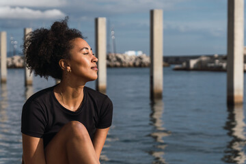 Young woman relaxing by the sea, breathing fresh air and enjoying a peaceful moment of mindfulness