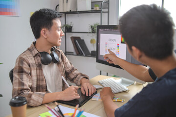Design Team Discussing Logo Concepts and Color Schemes on Computer Monitor