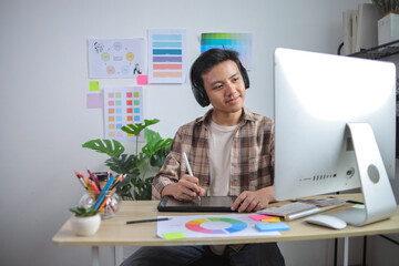 Smiling Graphic Designer in Plaid Shirt and Headphones Working Digitally on Tablet at Modern