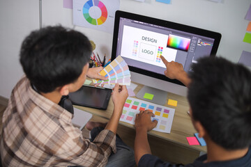 Two Young Asian Graphic Designers Collaborating While Selecting Color Palette for Logo Design