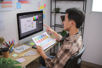 Young Graphic Designer Pointing at Monitor While Comparing Color Sheet to Digital Logo Design