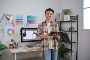 Smiling Male Designer Holding Tablet in His Organized Workspace, Showcasing Logo Design Development
