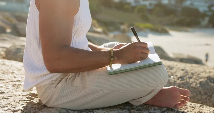 Man, hands and writing by ocean with journal for goal setting, personal growth or process emotions. Daily reflection, notes or person at beach with diary for self improvement, inspiration or insight.