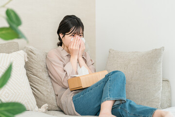 Young Asian woman wiping tears while watching TV or movie on sofa