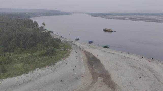 Aerial view of Morjim turtle nesting beach in Goa during winter, showing small fishing boats along the shoreline, gentle ocean waves, sandy coast, and the Chapora River visible in the background.