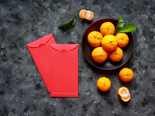 Top view of Mandarin oranges in a plate and two red envelopes for celebrating Chinese New Year.