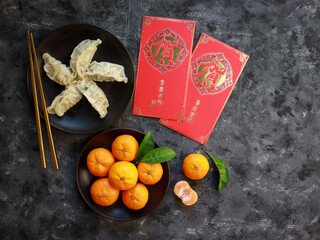 Top view of Mandarin oranges and dumpling in a plate and two red envelopes for celebrating Chinese New Year.