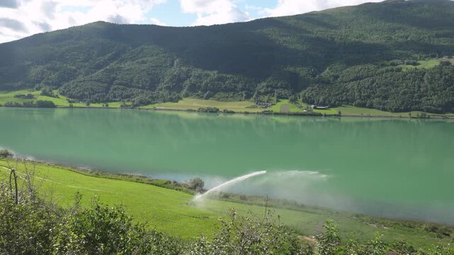 Green Hills and Farmland Slope Down Toward the Calm Turquoise Waters of Otta Lake Near Lom, Norway - Static Shot