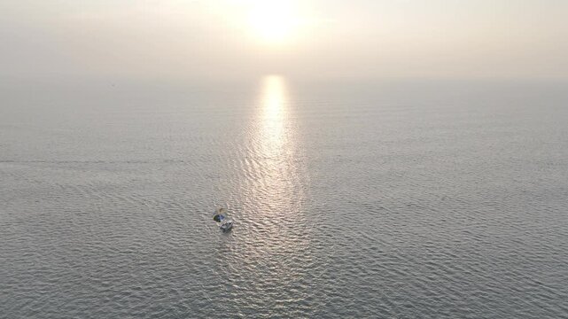 Sunset view of Mobor Beach in South Goa during winter, featuring parasailing boat and fishing boats on the Arabian Sea, with golden sunlight reflecting on calm water under a warm evening sky.