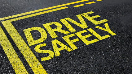 Drive safely message on asphalt road with yellow markings