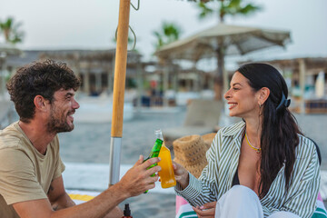 Happy couple enjoying drinks making a toast on beach vacation