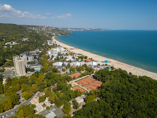 Aerial view of Albena resort in Bulgaria with sandy beach, turquoise Black Sea, hotels, forested hills and tennis courts. Popular summer vacation destination seen from above