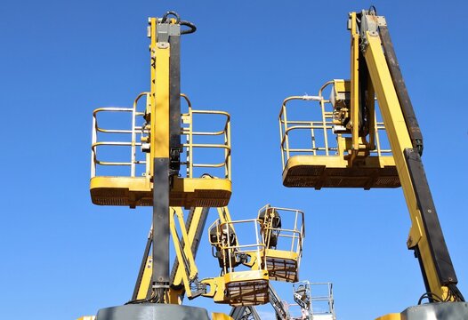 Rear and side view of  cherry picker buckets with blue sky on background.