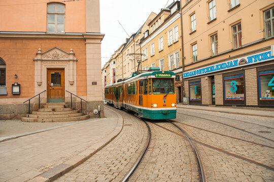 Vintage-style tramway car rides on a paved street through the old european city. Norrkoeping, Sweden