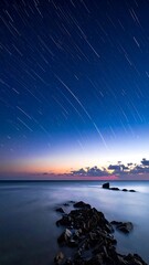 Long exposure shot of star trails over the ocean at twilight