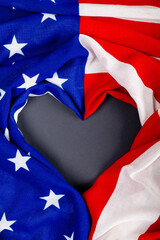 Overhead view of crumpled usa flag making heart shape on black table