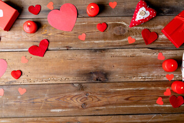 Burning red candles with heart shapes decorations by gift box on wooden table with copy space