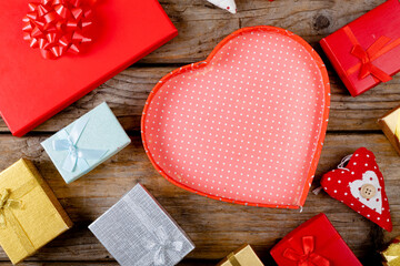 Overhead view of empty red heart shape gift box with copy space amidst presents on wooden table