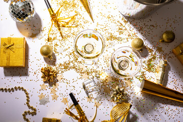 Champagne glasses on scattered confetti with gift and decoration on table