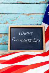 Happy presidents day text on writing slate with usa flag on blue wooden table with copy space