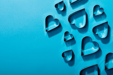 Directly above shot of heart shaped cookie cutters arranged on blue background, copy space