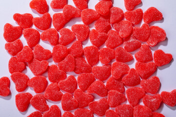 Overhead view of heart shaped red candies on white background, copy space