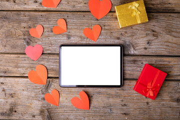 Directly above shot of tablet pc by gifts and heart shaped decoration on table, copy space