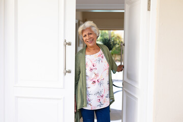 Portrait of african american senior woman smiling while standing at the front door of the house