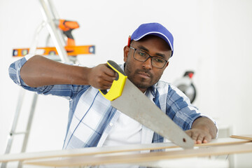 a man carpenter cuts a wooden beam