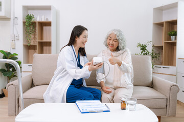 Obraz premium Female doctor checking old woman blood pressure at clinic and filling patient history in the morning.