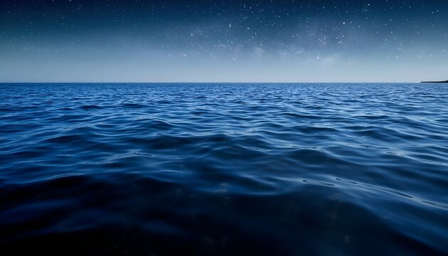 Ocean view under starry night sky reflecting dark blue water and horizon