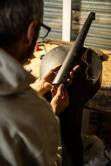 Luthier Works on Carbon Fiber Cello Neck Installation in a Workshop Setting