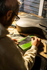 Skilled Luthier Shaping Carbon Fiber Parts in a Moody Workshop Environment
