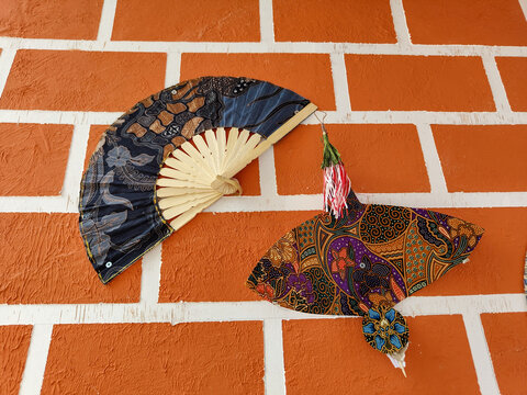 Kuala Lumpur, Malaysia - October 25, 2025 - Batik-patterned fans and bird-shaped decorations on an orange wall at the Kuala Lumpur Garden Festival exhibition at Taman Tasik Titiwangsa. "editorial only