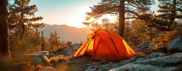 The tent glowing at sunrise on a rocky mountain campsite among pine trees