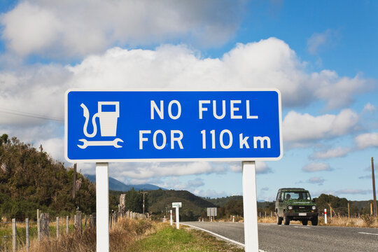 No fuel warning road sign on empty highway, West Coast, New Zealand