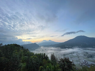 Panoramic morning view of Pinggan Village Bali with Mount Batur, Mount Abang and Mount Agung under cloudy sky