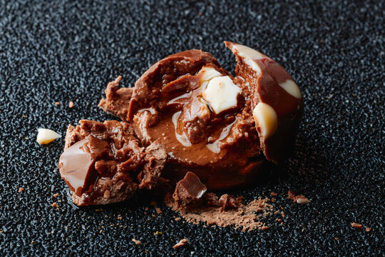 Crushed liquor chocolate candy with leaking cream filling on black surface