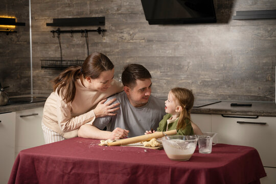 Family baking together at home kitchen with flour and rolling pin