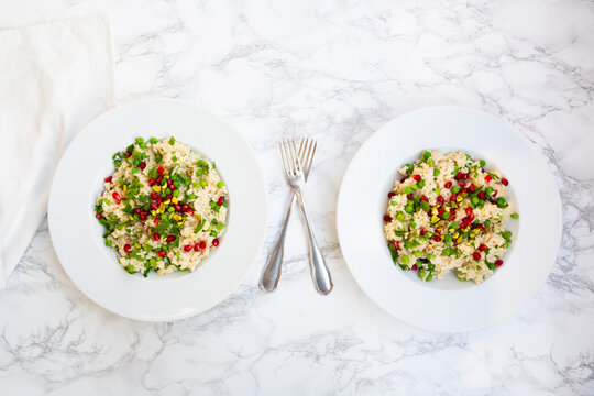 Vegetarian risotto with peas pistachio and pomegranate seed on marble