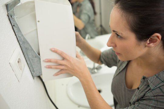 woman installing an electric hand dryer in a restroom