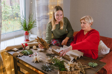 Grandmother and grandmother making eco friendly Christmas paper crafts in cozy home