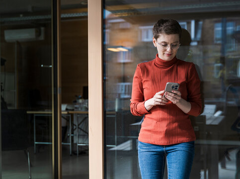 Woman in modern office using smartphone and smiling