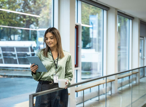 Professional using tablet and holding coffee in modern office interior