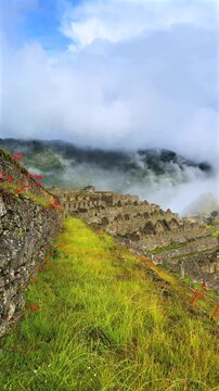 Morning sunrise Machu Picchu Inca trail tourist circuit terrances landscape sunny foggy clouds Peruvian Andes Peru Per&uacute; historic Inca Sanctuary Temple rainy season lush green jungle Vertical pan right