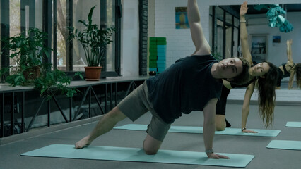 People in a balancing yoga pose in a bright studio