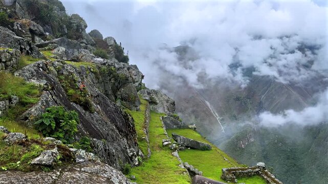 Machu Picchu highlands tourist circuit landscape fog cloudy morning Peru Per&uacute; aerial drone rainy season lush green jungle Peruvian Andes historic Inca Temple Sanctuary terrace layers pan right motion