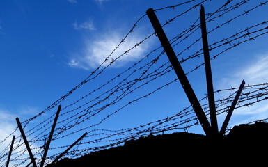Barbed wire fence against blue sky.