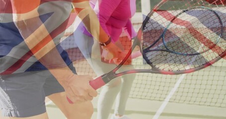 senior duo swinging rackets near net, holding balls, showing Union Jack overlay for sport marketing